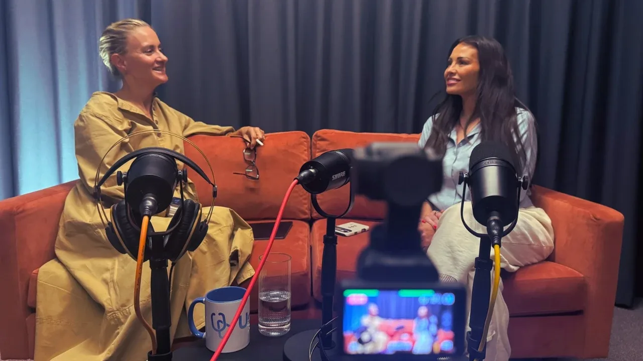 A business podcast conversation being filmed on an orange sofa