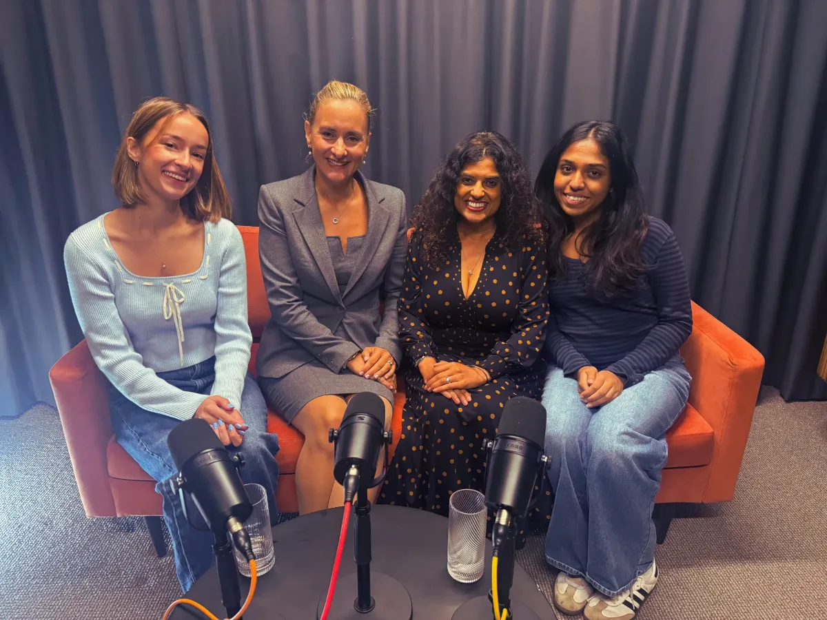 Four podcast guests smiling on an orange sofa behind microphones at Great Portland Street Studio
