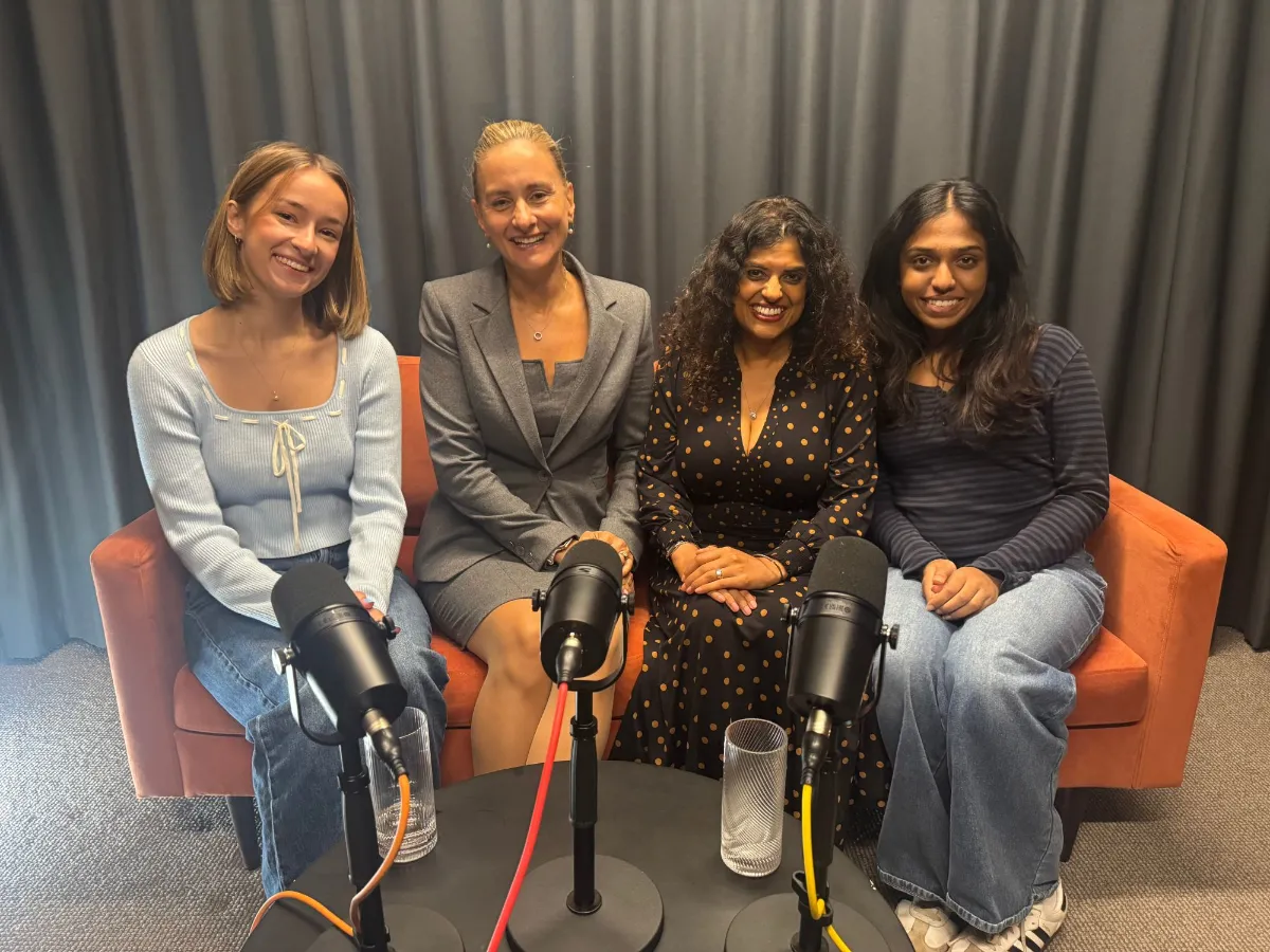 Four podcast guests smiling on an orange sofa behind microphones at Hale House